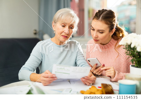 Mother and daughter paying bills with smartphone 111154535