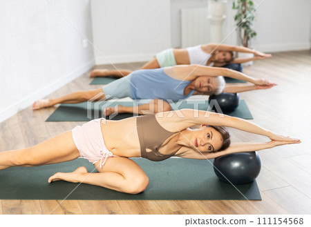 Family of three generations doing soft ball pilates exercises during group pilates class in studio Family of three generations doing soft ball pilates exercises during group pilates class in studio 111154568