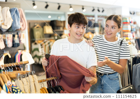 Young couple choosing convenient hoodie in clothing store 111154625