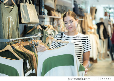 she browses through assortment of stylish sweaters 111154632
