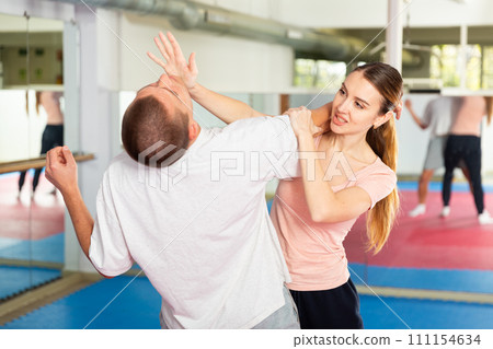 Young woman practicing palm strike with man in self defense training Young woman practicing palm strike with man in self defense training 111154634