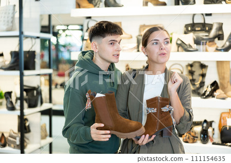 Guy male friend strongly recommends his young woman colleague to pay attention to model of boots 111154635