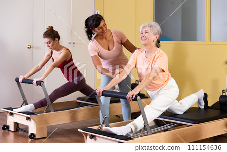 Two active women perform an exercise using a reformer bed 111154636