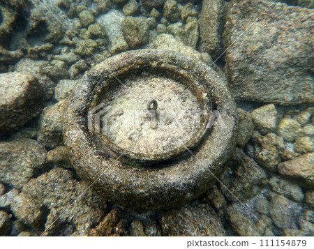 Old tire sits on top of sandy rocks underwater Old tire sits on top of sandy rocks underwater 111154879