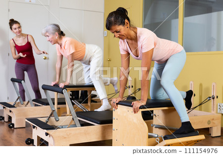 Hispanic woman practicing pilates stretching exercises on combo chair 111154976