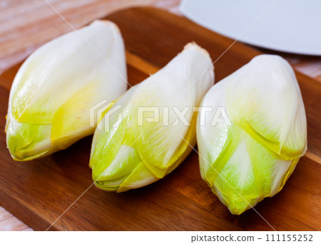 Raw organic endives on wooden table 111155252