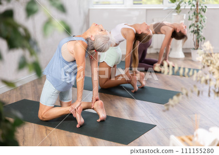 Senior woman standing in backbend asana Ustrasana in yoga studio Senior woman standing in backbend asana Ustrasana in yoga studio 111155280