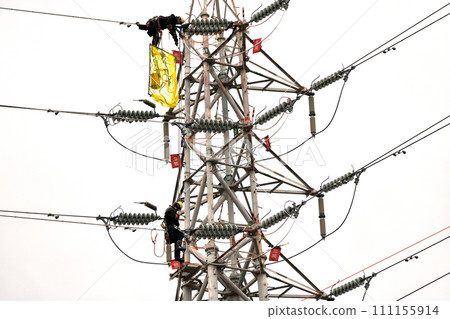 Maintenance work on a power transmission tower carried out in light rain - work scene of power line electricians Maintenance work on a power transmission tower carried out in light rain - work scene of power line electricians 111155914