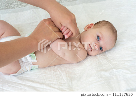 Mother's hands do gymnastics with the baby. Arms crossed on chest 111157630