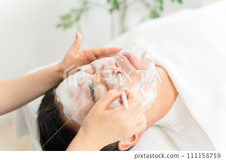 Male and female staff cleaning and cleansing the pores of the nose at a men's facial beauty salon 111158759