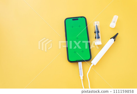 Mockup Ear Scope For Wax Removal Tool and Smartphone with Chroma Key Green Screen. Digital Otoscope, Earwax Cleaner With Gyroscope, Camera, Light. Cleaning Ears Device Connected to Phone. Copy Space, Mockup Ear Scope For Wax Removal Tool and Smartphone with Chroma Key Green Screen. Digital Otoscope, Earwax Cleaner With Gyroscope, Camera, Light. Cleaning Ears Device Connected to Phone. Copy Space, 111159858