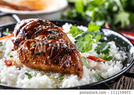 Grilled chicken breast served in a pan with jasmine rice and chili peppers Grilled chicken breast served in a pan with jasmine rice and chili peppers 111159955