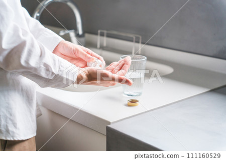Sick man taking oral medicine, supplements, and medicines in the kitchen / Medication Sick man taking oral medicine, supplements, and medicines in the kitchen / Medication 111160529