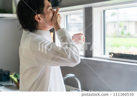 Sick man taking oral medicine, supplements, and medicines in the kitchen / Medication 111160530