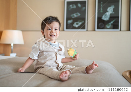 Baby boy's sitting on a bed wearing a suit Baby boy's sitting on a bed wearing a suit 111160632