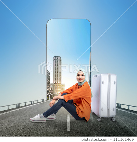 Asian girl in a scarf sitting with a suitcase on the street with a city view on the mobile phone screen Asian girl in a scarf sitting with a suitcase on the street with a city view on the mobile phone screen 111161469