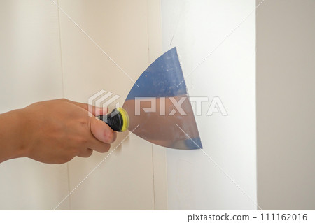 Man repairing crack white wall with spatula Man repairing crack white wall with spatula 111162016