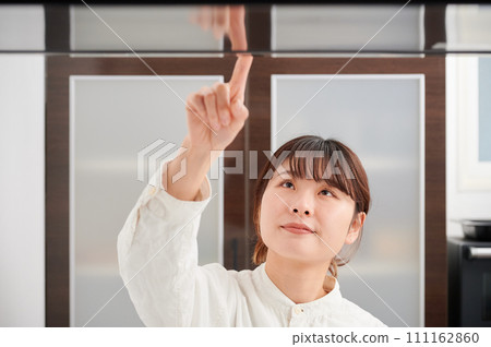 操作換氣扇清潔抽油煙機的婦女 操作換氣扇清潔抽油煙機的婦女 111162860