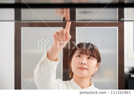 操作換氣扇清潔抽油煙機的婦女 操作換氣扇清潔抽油煙機的婦女 111162861