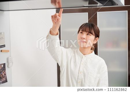 操作換氣扇清潔抽油煙機的婦女 操作換氣扇清潔抽油煙機的婦女 111162862
