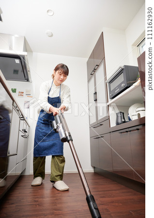 Woman holding a vacuum cleaner cleaning kitchen housewife Woman holding a vacuum cleaner cleaning kitchen housewife 111162930