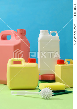 Front of plastic canisters with different sizes and colors decorated on blue background with cleaning tools. Mockup canister empty label for design. Household cleaning chemicals. Chemical substances 111163021