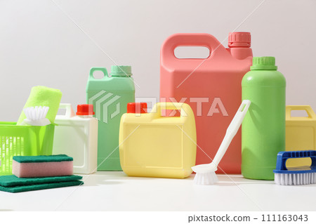 Front view of different bottle and canisters mockup of detergent product displayed on white background with cleaning tools. Housework and professional cleaning service supplies. Front view of different bottle and canisters mockup of detergent product displayed on white background with cleaning tools. Housework and professional cleaning service supplies. 111163043