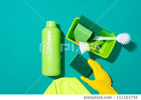 Top view of green household cleaning supplies displayed against a turquoise background. Mockup of cleaning products for advertising. Empty label, top view. Top view of green household cleaning supplies displayed against a turquoise background. Mockup of cleaning products for advertising. Empty label, top view. 111163756