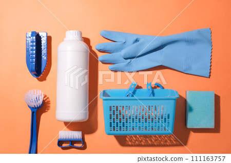 Toilet brush, a bottle of toilet cleaner, rubber gloves and plastic basket on a orange background. Clean the bathroom with necessary items. Copy space for ads. 111163757