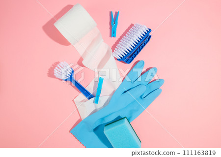 Cleaning product tool equipments: blue rubber glove, brushes, sponge and paper roll decorated on a pink background. Top view, advertising photo, concept of cleanliness, cleaning services. Cleaning product tool equipments: blue rubber glove, brushes, sponge and paper roll decorated on a pink background. Top view, advertising photo, concept of cleanliness, cleaning services. 111163819