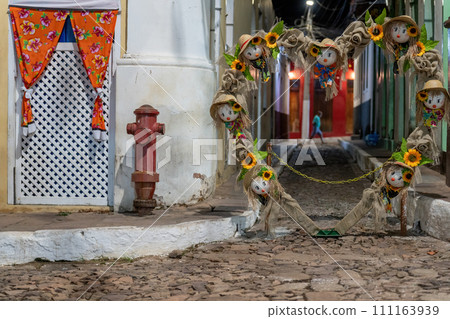 Colorful Scarecrow Decorations Adorning a Cobblestone Street 111163939