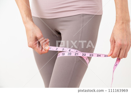 中年婦女測量她腿的大腿 中年婦女測量她腿的大腿 111163969