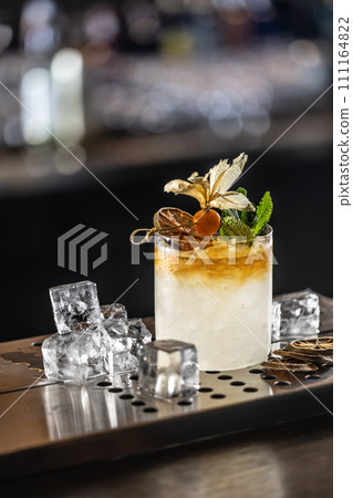Exotic Mai Tai cocktail drink decorated with physalis and mint on the bar counter of the pub 111164822