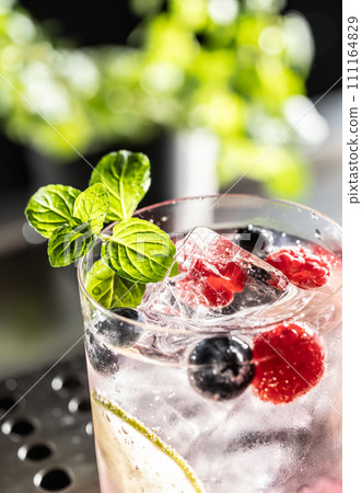 Pink cocktail Gin Tonic drink with raspberries, blueberries, lime and fresh mint 111164829