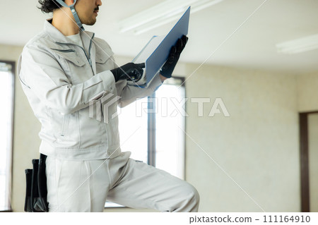 A man in work clothes inspecting the ceiling 111164910