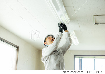A man in work clothes inspecting the ceiling 111164914