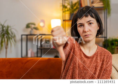 Woman showing thumbs down sign gesture, expressing discontent, disapproval dissatisfied dislike 111165431