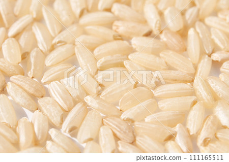 A background of dry brown rice grains showcases the integral, uncooked texture 111165511