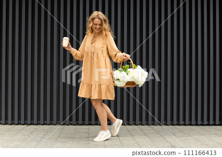 Beautiful girl with flowers on the street in summer. 111166413