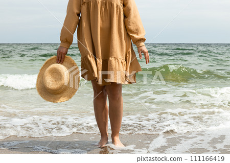 A girl in a dress walks on the beach in the summer. 111166419