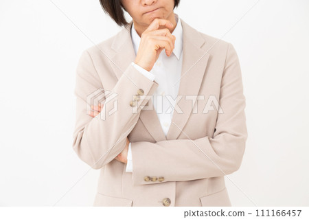 A middle-aged woman in a suit worries with her arms crossed 111166457