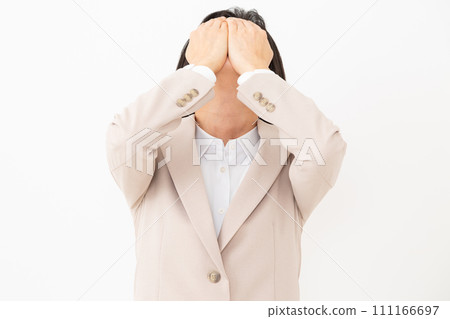 一名身穿西裝的中年婦女遮住臉,痛苦不堪 一名身穿西裝的中年婦女遮住臉,痛苦不堪 111166697