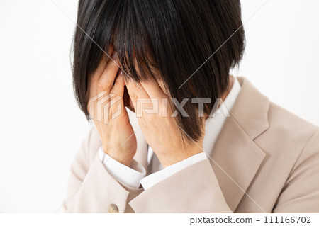 A middle-aged woman in a suit covering her face and suffering A middle-aged woman in a suit covering her face and suffering 111166702