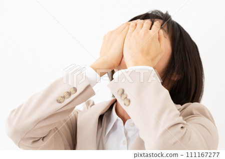 一名身穿西裝的中年婦女遮住臉,痛苦不堪 一名身穿西裝的中年婦女遮住臉,痛苦不堪 111167277