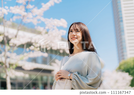 Female college student walking through cherry blossom campus 111167347