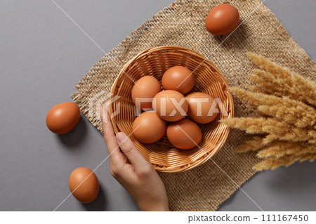 Eggs in a wicker basket, on a gray background. 111167450