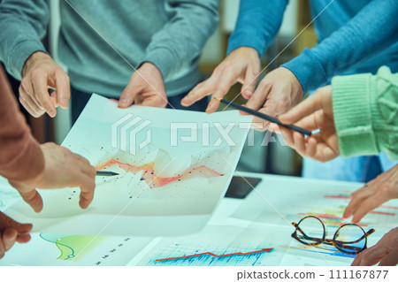 Individuals examining and discussing a complex data visualization sheet among other graphs. Collages working with analytical graphs Individuals examining and discussing a complex data visualization sheet among other graphs. Collages working with analytical graphs 111167877