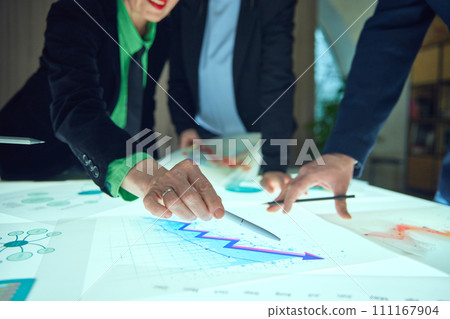 Group of employees working with analytical papers, checking graphs and discussing possible growth. Statistics, growth and analysis Information 111167904
