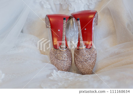 shoes of the bride with wedding rings on the floor 111168634