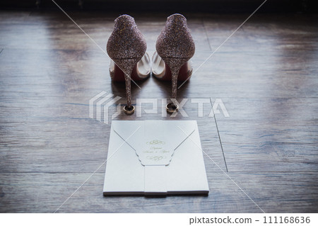 shoes of the bride with wedding rings on the floor 111168636